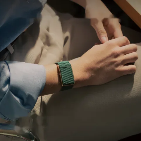 Person wearing a green Speediance Strap while resting a hand on their knee